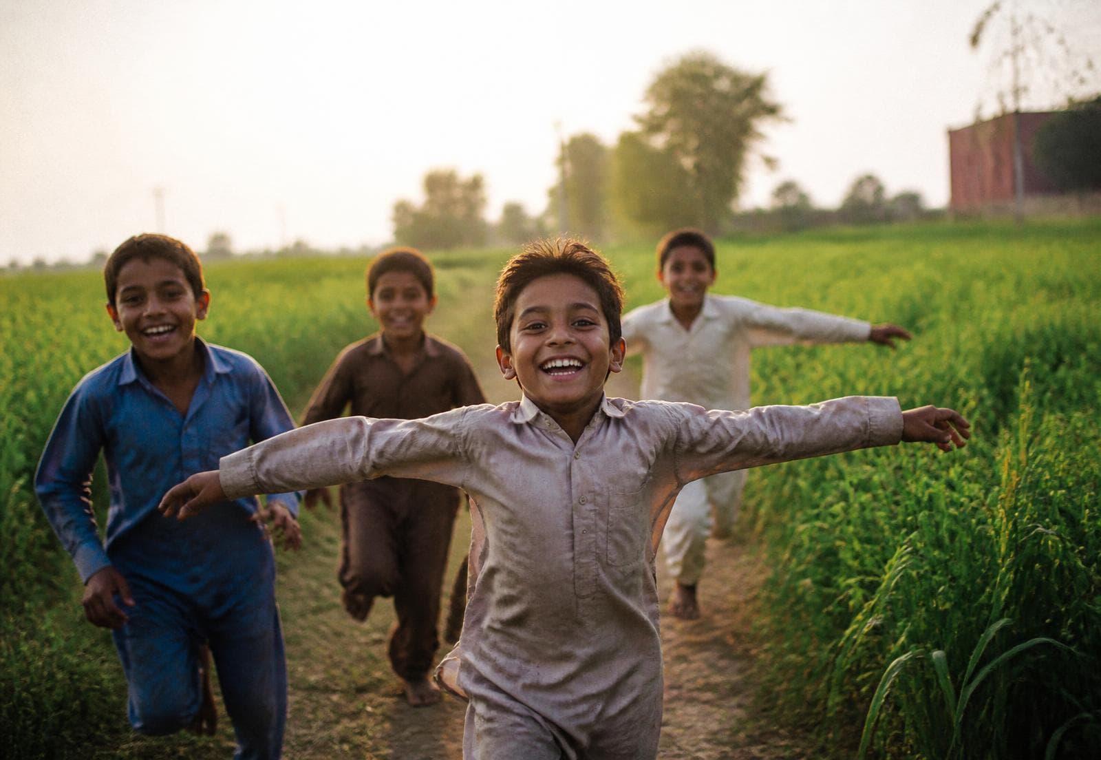 Children running joyfully through a green field